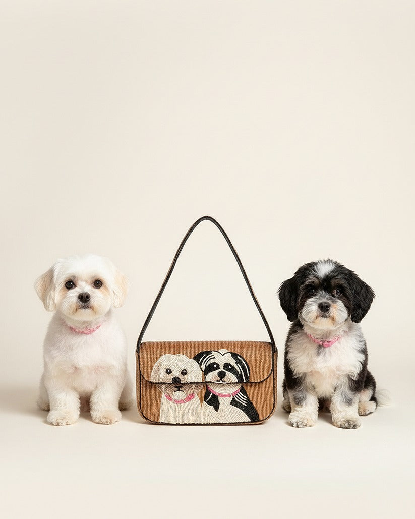 Two small dogs standing on either side of a handbag with dog illustrations on a beige background